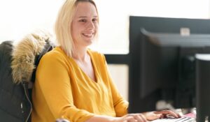 Collaboratrice immo jaune travaillant a son ordinateur